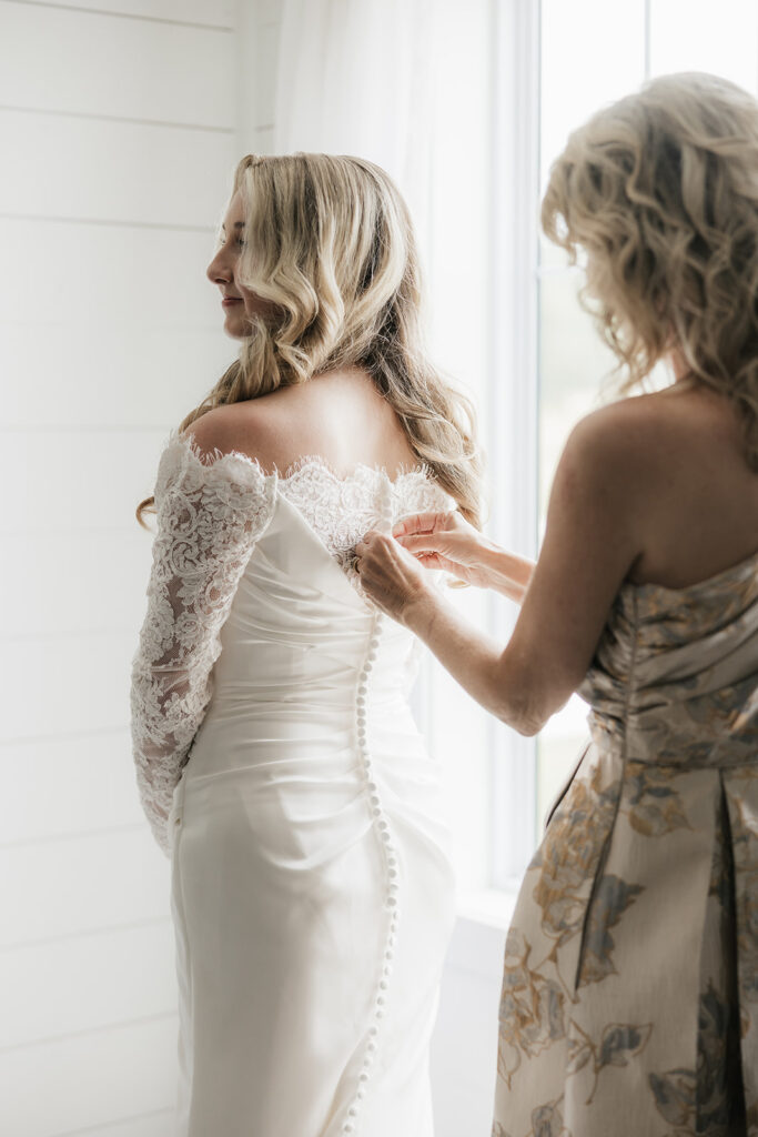 mother of the bride helping her with the wedding dress