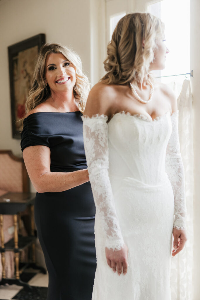 mother of the bride helping her with the wedding dress
