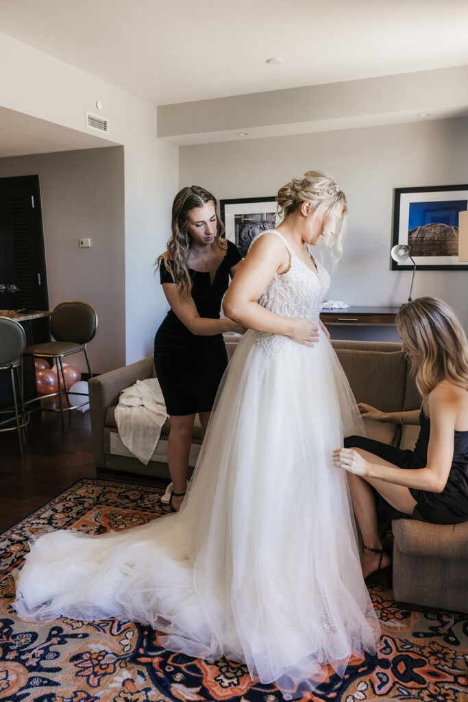 bridesmaids helping the bride with her wedding dress