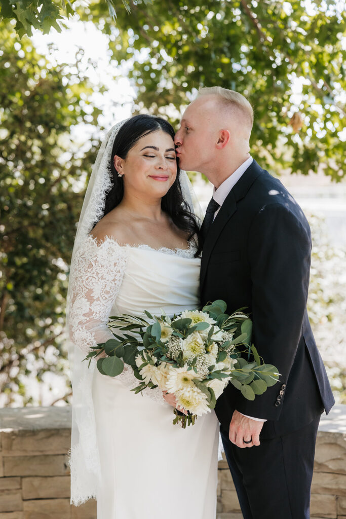 groom kissing the bride on the forehead