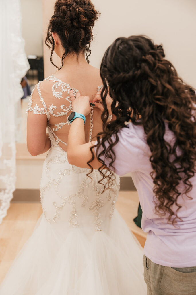 Sister of the bride, helping her with the wedding dress